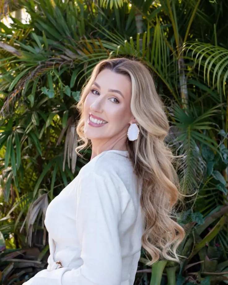 Fernanda Angnes sorrindo, de branco, num jardim